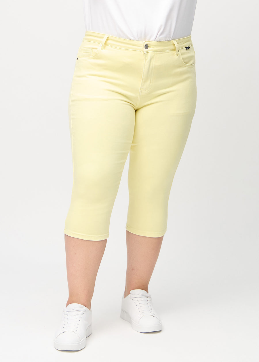 Skinny-capris til kvinner i pastellgult jeansstoff, fargen Lemonades. Sett forfra på en plus size-modell, med tettsittende ben til rett under kneet.