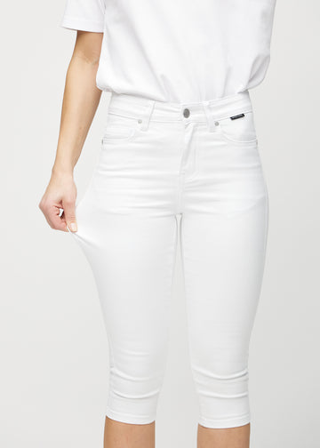 Skinny-capris til kvinner i hvitt jeansstoff, fargen Marguerites. En modell strekker stoffet for å vise fleksibiliteten.