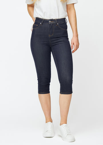 Dyp mørkeblå denim capris til dame i fargen Midnights med skinny passform som sitter tett fra hoften til under kneet, sett forfra.