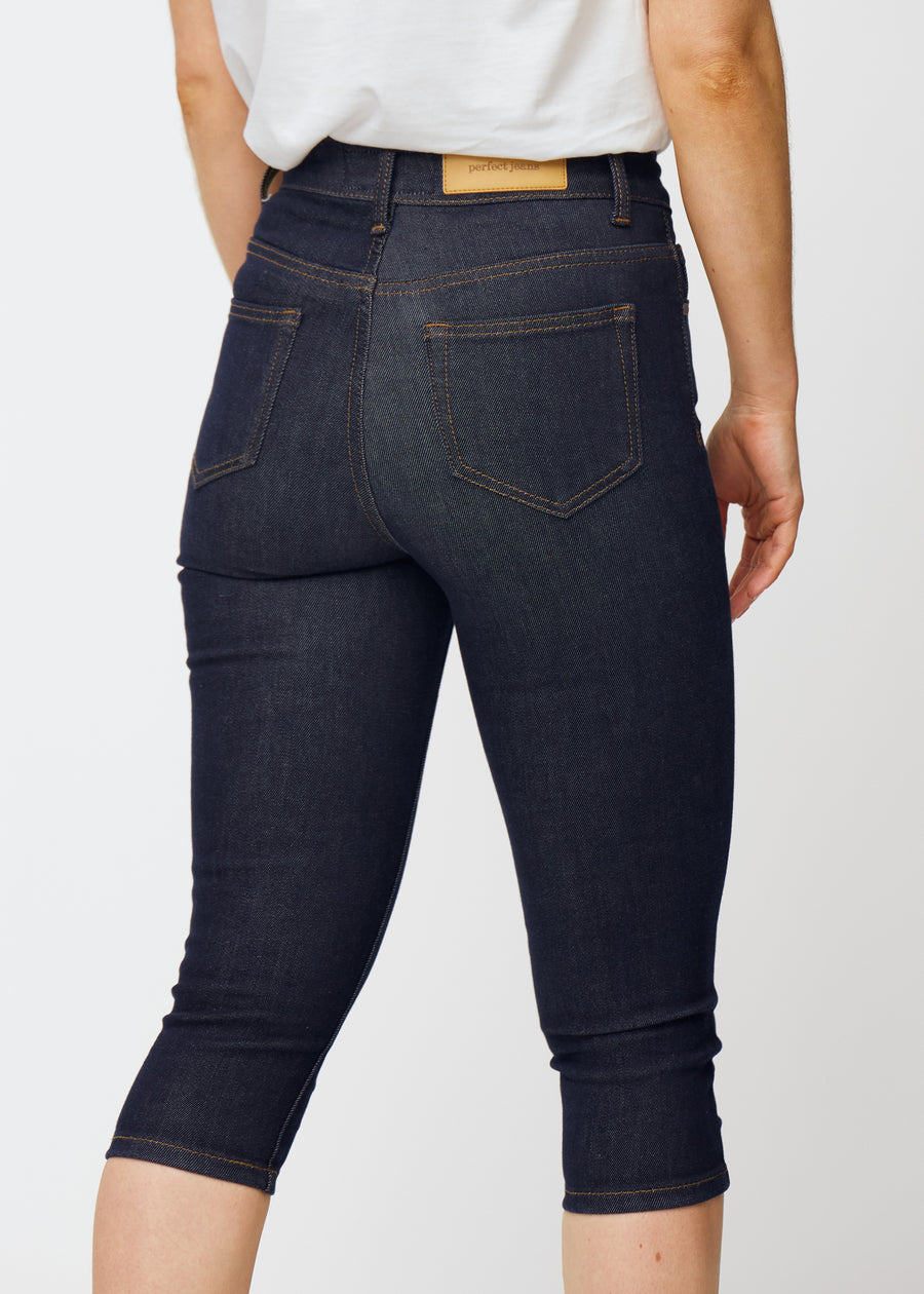 Dyp mørkeblå denim capris til dame i fargen Midnights sett bakfra i nærbilde for å vise passform og detaljer.