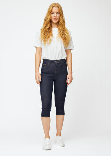 Helbilde av modell i dyp mørkeblå denim capris til dame i fargen Midnights med skinny passform.