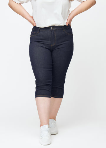 Dyp mørkeblå denim capris til dame i fargen Midnights med skinny passform sett forfra på plus-size modell.