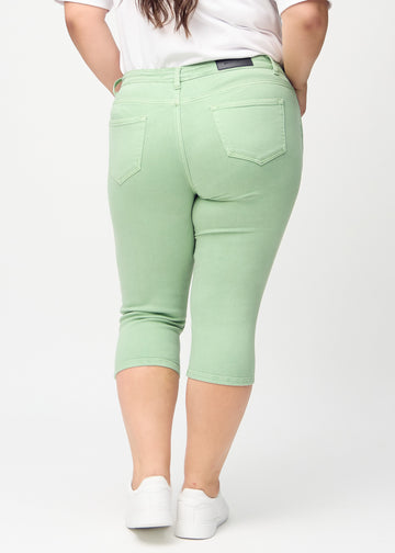 Skinny-capris til kvinner i pastellgrønt jeansstoff, fargen Mints. Sett bakfra på en plus size-modell, med fokus på passform og baklommer.