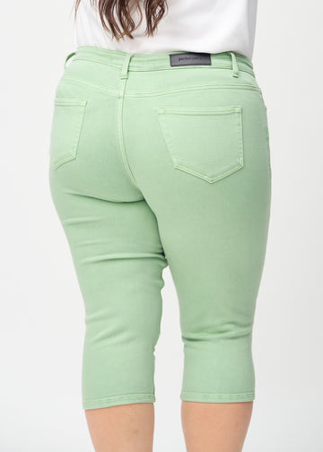 Skinny-capris til kvinner i pastellgrønt jeansstoff, fargen Mints. Nærbilde bakfra på en plus size-modell, med fokus på lommer og sømmer.