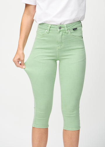 Skinny-capris til kvinner i pastellgrønt jeansstoff, fargen Mints. En modell strekker stoffet for å vise fleksibiliteten.
