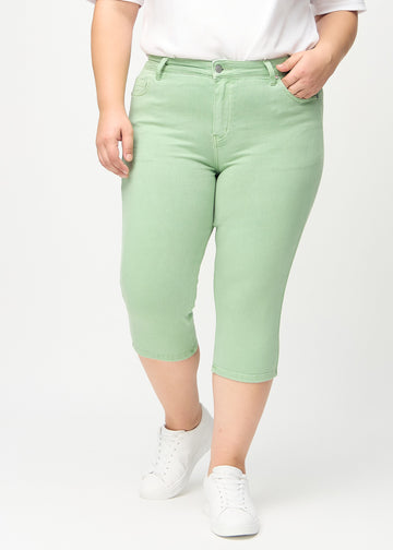 Skinny-capris til kvinner i pastellgrønt jeansstoff, fargen Mints. Sett forfra på en plus size-modell, med tettsittende ben til rett under kneet.