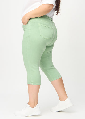 Skinny-capris til kvinner i pastellgrønt jeansstoff, fargen Mints. Sett fra siden på en plus size-modell, med tettsittende passform.