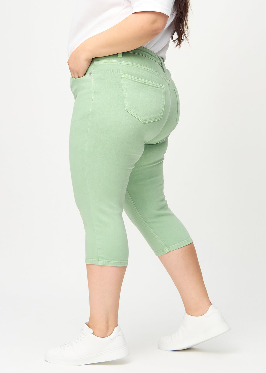 Skinny-capris til kvinner i pastellgrønt jeansstoff, fargen Mints. Sett fra siden på en plus size-modell, med tettsittende passform.