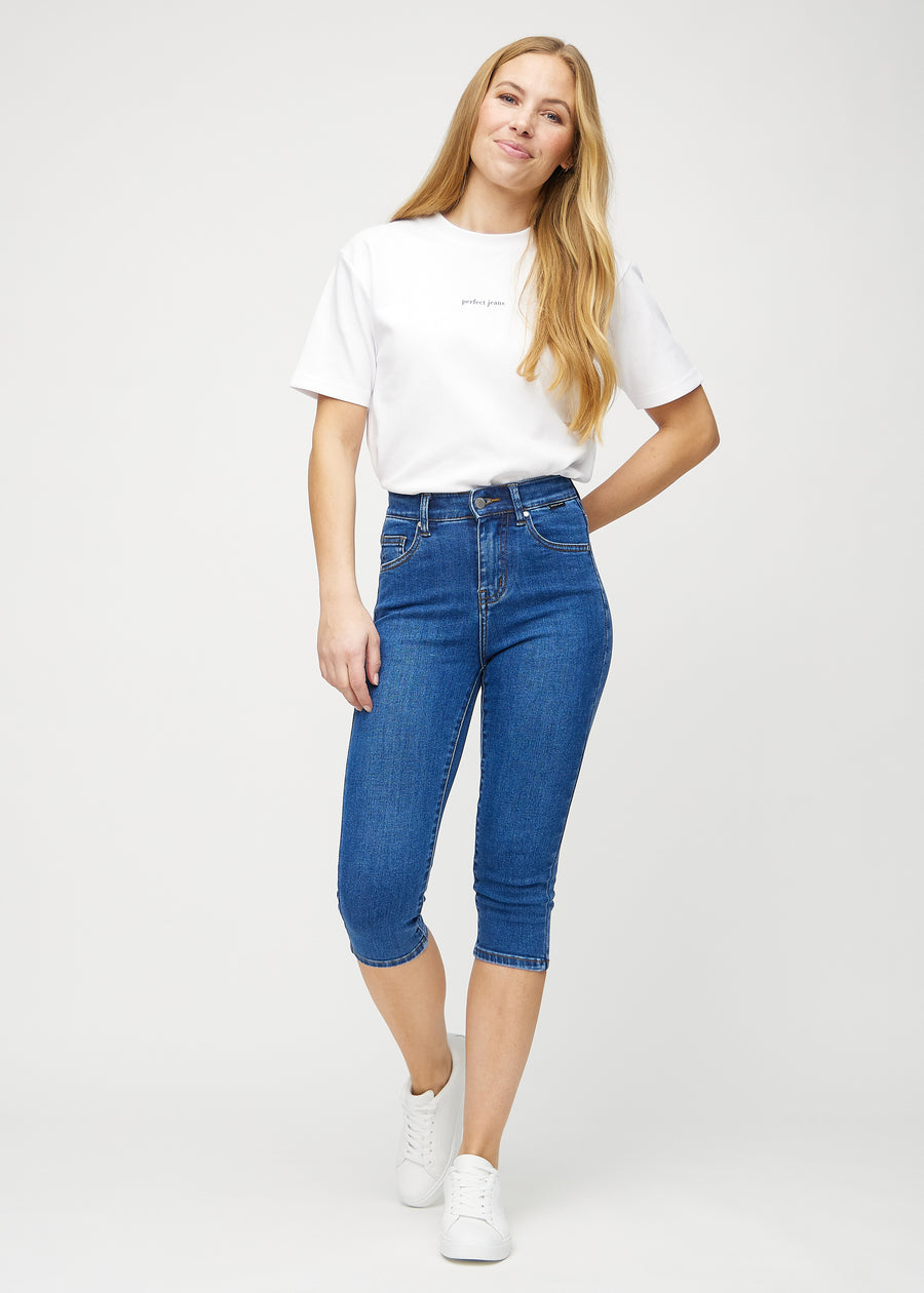 Skinny-capris til kvinner i mørkeblå denim, fargen Oceans. Helhetsbilde av en modell med capris på.