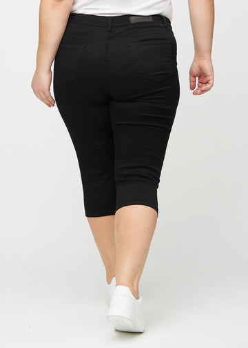Svarte skinny capris sett bakfra på en plus-size-modell, slik at man kan se hele produktet.