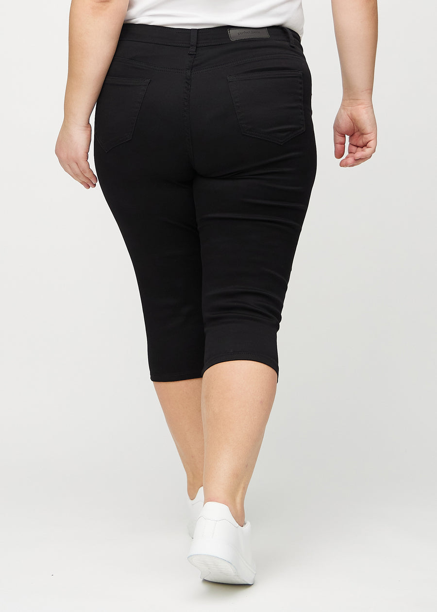 Svarte skinny capris sett bakfra på en plus-size-modell, slik at man kan se hele produktet.