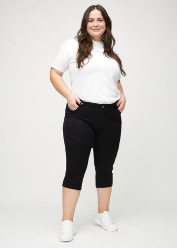 Fullt bilde av en plus-size-modell i svarte skinny capris.