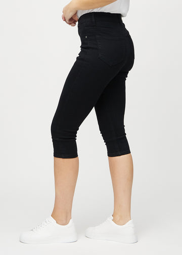 Svarte skinny capris sett fra siden på modell.