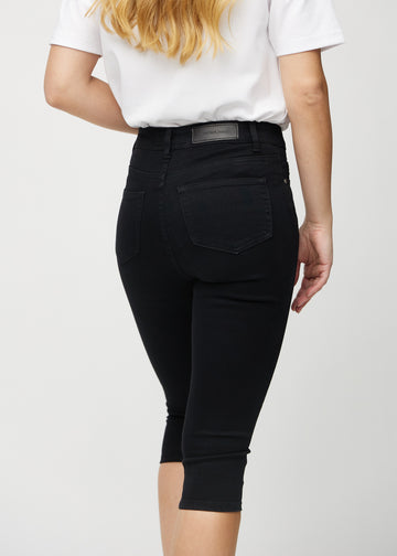 Svarte skinny capris sett bakfra på nært hold for å vise detaljer.