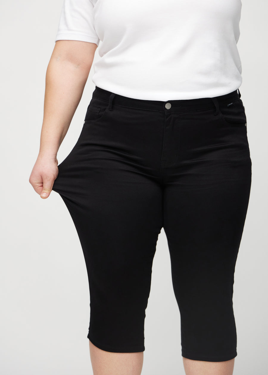 Plus-size-modellen strekker caprisene ved låret for å vise stretch.
