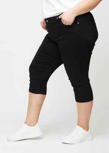 Svarte skinny capris sett fra siden på en plus-size-modell.