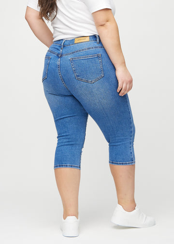 Skinny-capris til kvinner i blå denim, fargen Rivers. Sett bakfra på en plus size-modell, med fokus på passform og baklommer.