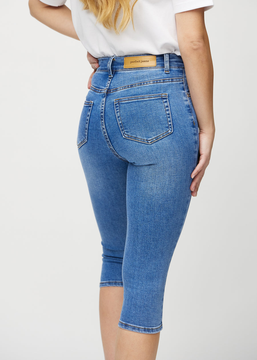 Skinny-capris til kvinner i blå denim, fargen Rivers. Nærbilde bakfra på en modell, med fokus på lommer og sømmer.