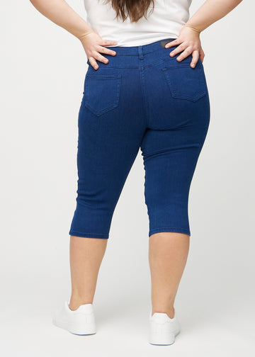 Skinny-capris til kvinner i mørkeblått jeansstoff, fargen Royals. Sett bakfra på en plus size-modell, med fokus på passform og baklommer.