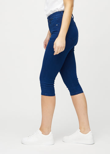 Skinny-capris til kvinner i mørkeblått jeansstoff, fargen Royals. Sett fra siden på en modell, med tettsittende passform.