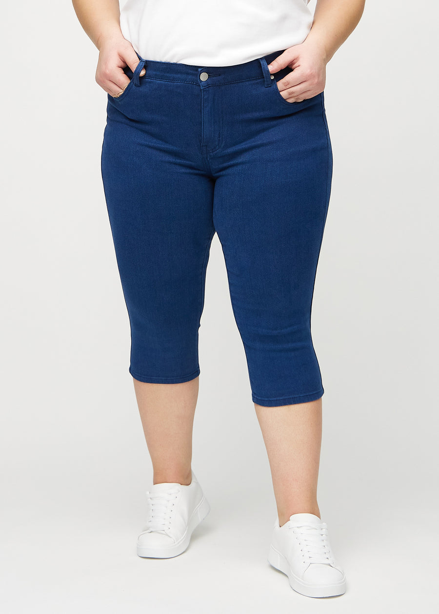 Skinny-capris til kvinner i mørkeblått jeansstoff, fargen Royals. Sett forfra på en plus size-modell, med tettsittende ben til rett under kneet.
