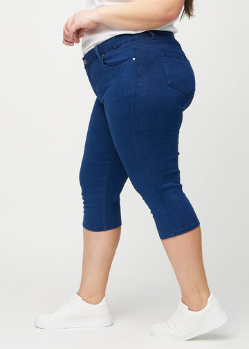 Skinny-capris til kvinner i mørkeblått jeansstoff, fargen Royals. Sett fra siden på en plus size-modell, med tettsittende passform.