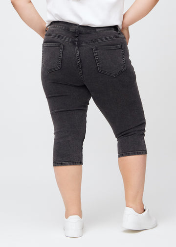 Skinny-capris til kvinner i mørkegrå denim, fargen Shadows. Sett bakfra på en plus size-modell, med fokus på passform og baklommer.