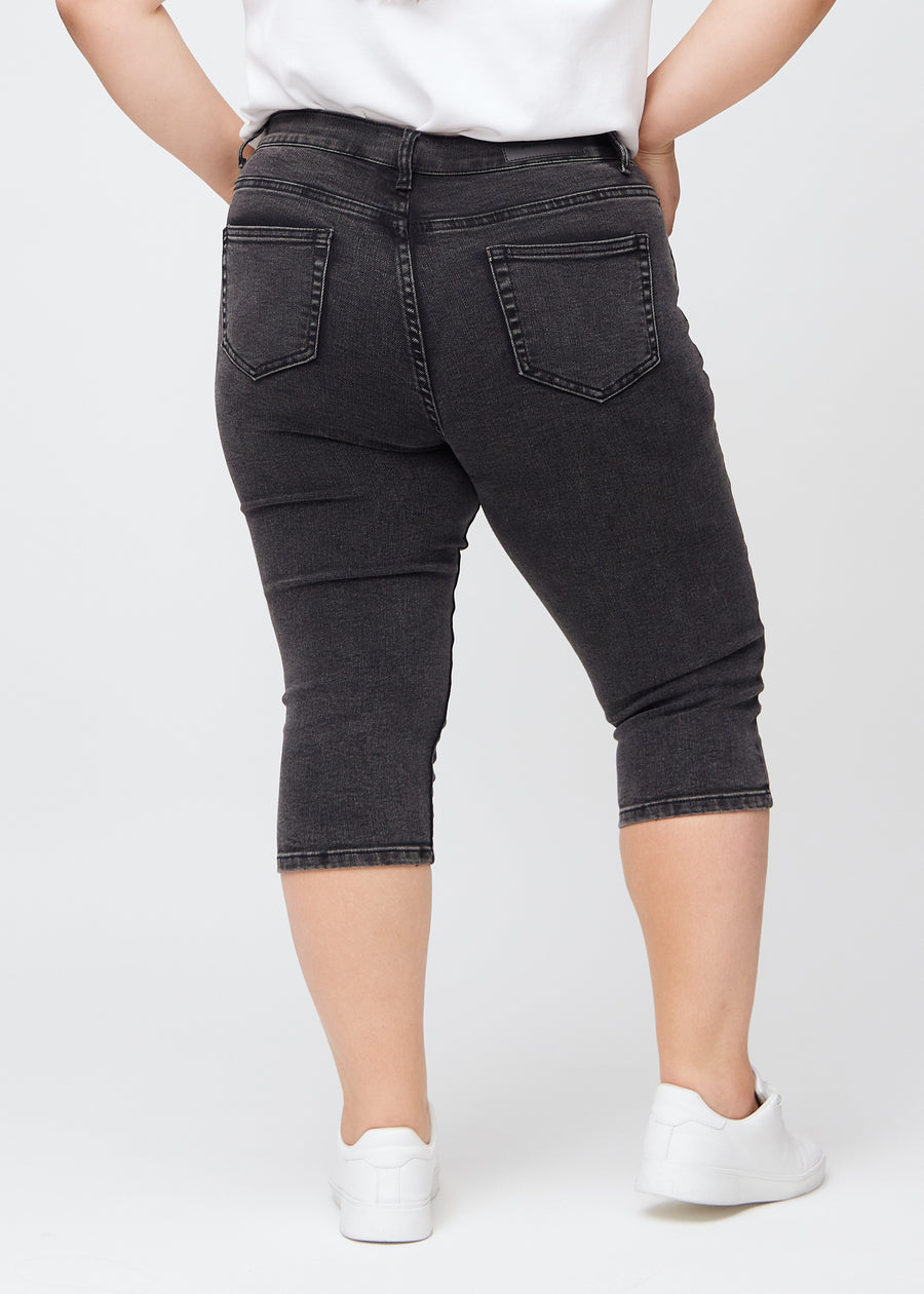 Skinny-capris til kvinner i mørkegrå denim, fargen Shadows. Sett bakfra på en plus size-modell, med fokus på passform og baklommer.