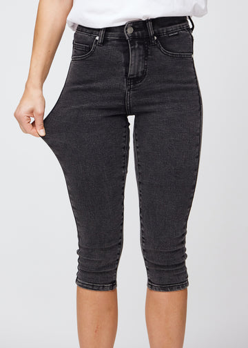 Skinny-capris til kvinner i mørkegrå denim, fargen Shadows. En modell strekker stoffet for å vise fleksibiliteten.