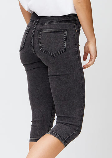 Skinny-capris til kvinner i mørkegrå denim, fargen Shadows. Nærbilde bakfra på en modell, med fokus på lommer og sømmer.