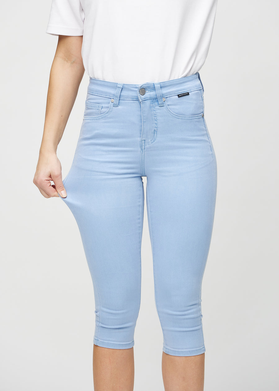 Skinny-capris til kvinner i lyseblått jeansstoff, fargen Skies. En modell strekker stoffet for å vise fleksibiliteten.