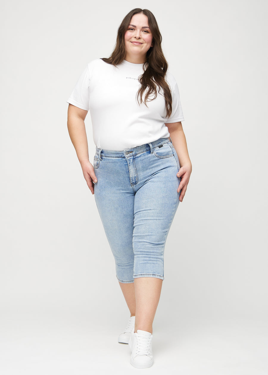 Skinny-capris til kvinner i lyseblå denim, fargen Waves. Helhetsbilde av en plus size-modell med capris på.