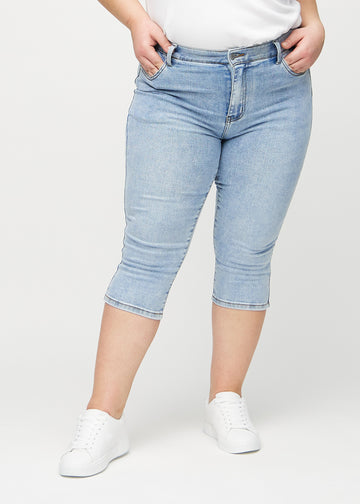 Skinny-capris til kvinner i lyseblå denim, fargen Waves. Sett forfra på en plus size-modell, med tettsittende ben til rett under kneet.
