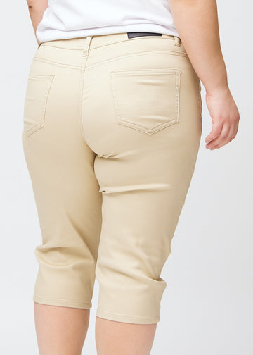 Slim-capris til kvinner i beige jeansstoff, fargen Gazelles. Nærbilde bakfra på en plus size-modell, med fokus på baklommer og sømmer.