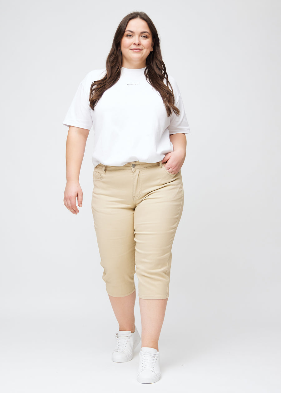 Slim-capris til kvinner i beige jeansstoff, fargen Gazelles. Helhetsbilde av en plus size-modell med slim-capris.