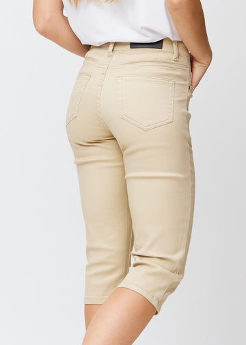 Slim-capris til kvinner i beige jeansstoff, fargen Gazelles. Nærbilde bakfra på en modell, med fokus på baklommer og sømmer.