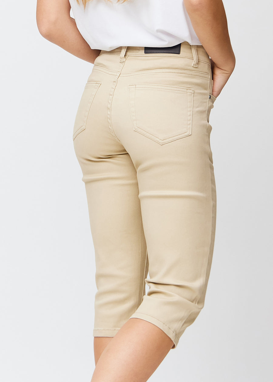 Slim-capris til kvinner i beige jeansstoff, fargen Gazelles. Nærbilde bakfra på en modell, med fokus på baklommer og sømmer.
