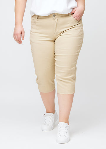 Slim-capris til kvinner i beige jeansstoff, fargen Gazelles. Sett forfra på en plus size-modell, med figursydd passform til rett under kneet.