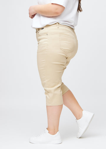 Slim-capris til kvinner i beige jeansstoff, fargen Gazelles. Sett fra siden på en plus size-modell, med figursydd passform og mellomhøyt liv (Mid Rise).