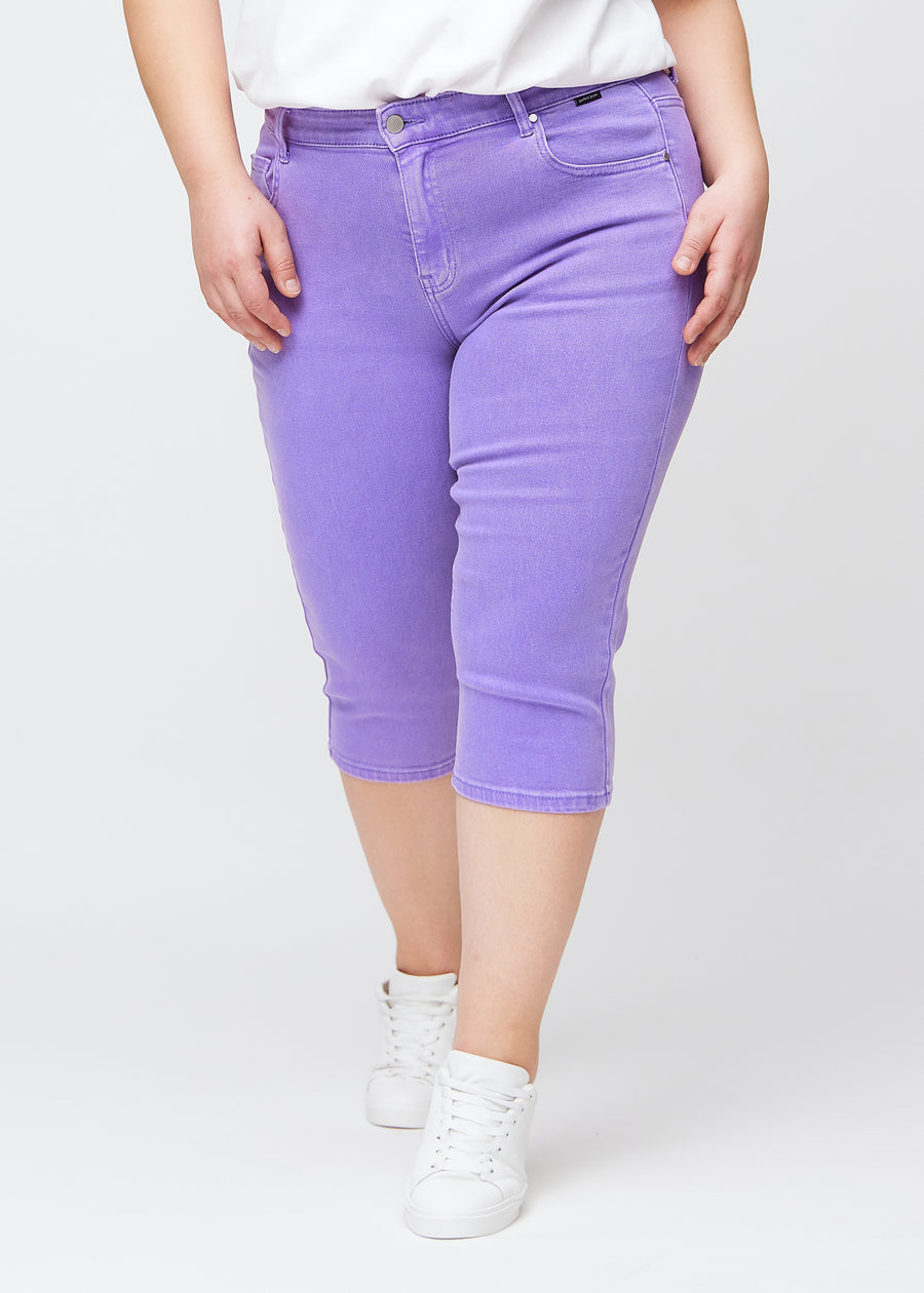 Slim-capris til kvinner i pastellilla jeansstoff, fargen Lavenders. Sett forfra på en plus size-modell, med figursydd passform til rett under kneet.