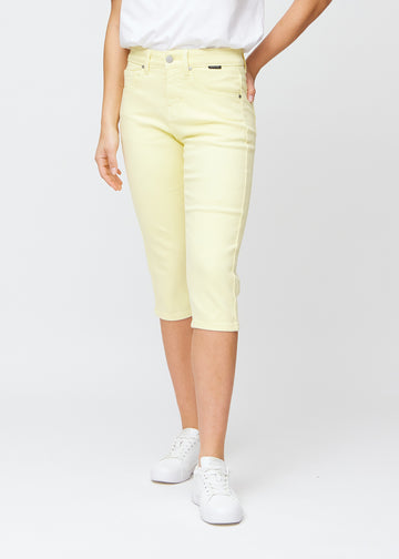 Slim-capris til kvinner i pastelllysegult jeansstoff, fargen Lemonades. Sett forfra på en modell, med figursydd passform til rett under kneet.
