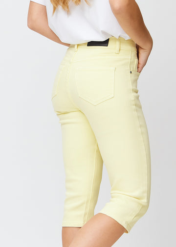 Slim-capris til kvinner i pastelllysegult jeansstoff, fargen Lemonades. Nærbilde bakfra på en modell, med fokus på baklommer og sømmer.