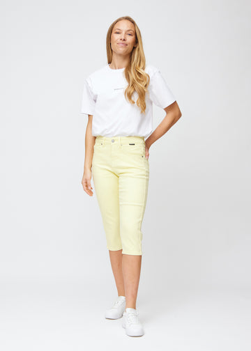 Slim-capris til kvinner i pastelllysegult jeansstoff, fargen Lemonades. Helhetsbilde av en modell med slim-capris.