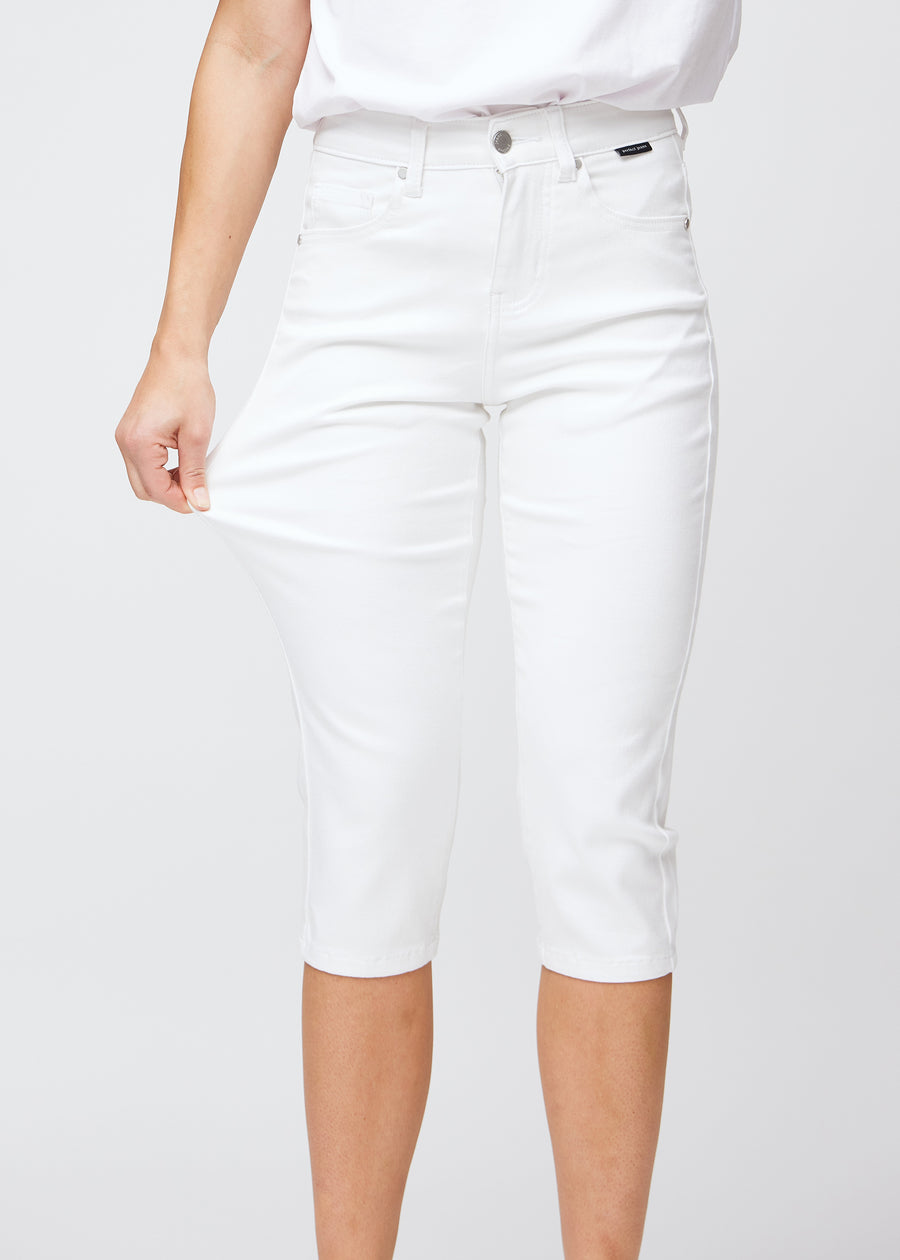 Slim-capris til kvinner i hvitt jeansstoff, fargen Marguerites. En modell strekker stoffet ved låret for å vise stretch og fleksibilitet.