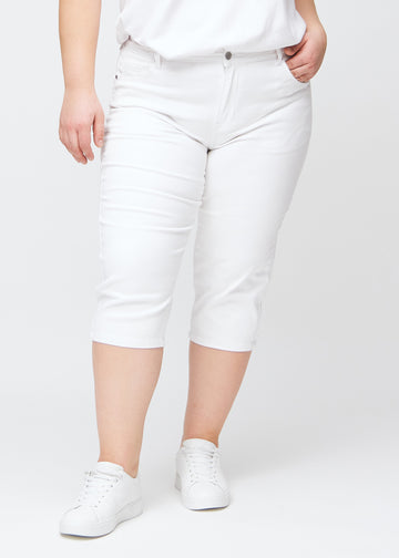 Slim-capris til kvinner i hvitt jeansstoff, fargen Marguerites. Sett forfra på en plus size-modell, med figursydd passform til rett under kneet.