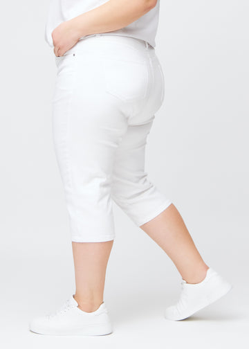 Slim-capris til kvinner i hvitt jeansstoff, fargen Marguerites. Sett fra siden på en plus size-modell, med figursydd passform og mellomhøyt liv (Mid Rise).