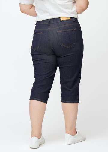 Dyp mørkeblå denim capris til dame i fargen Midnights sett bakfra på plus-size modell.