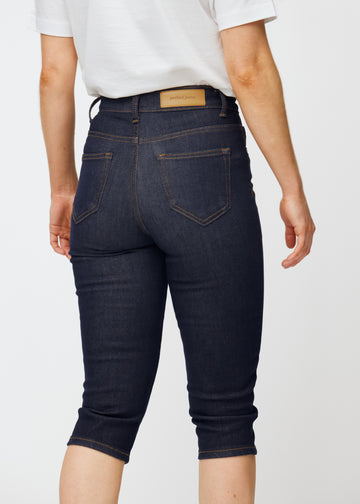 Dyp mørkeblå denim capris til dame i fargen Midnights sett bakfra i nærbilde for å vise passform og detaljer.