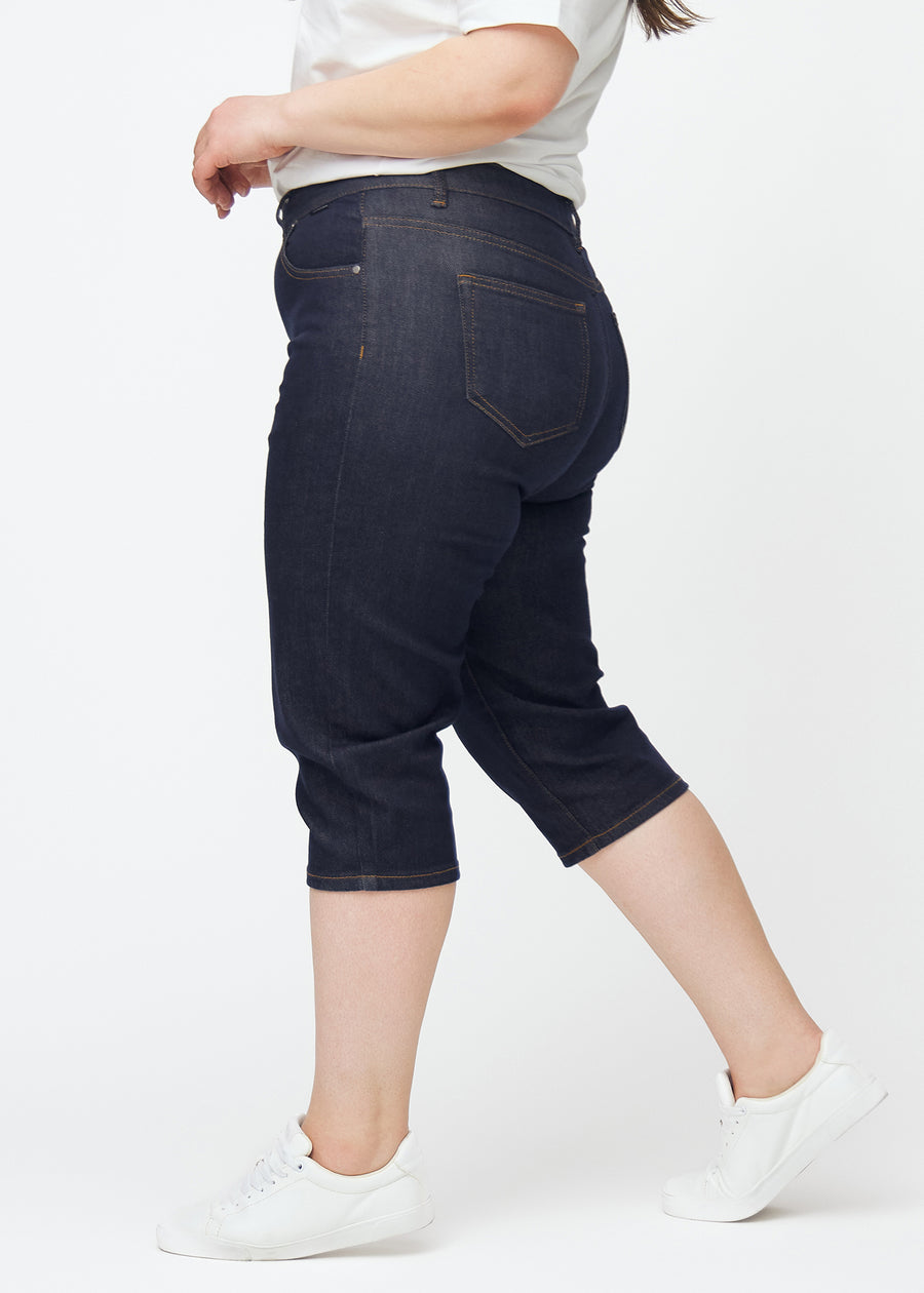 Dyp mørkeblå denim capris til dame i fargen Midnights med slim passform sett fra siden på plus-size modell.