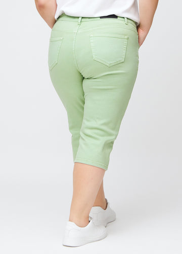 Slim-capris til kvinner i pastelllysegrønt jeansstoff, fargen Mints. Sett bakfra på en plus size-modell, med fokus på passform, lengde og baklommer.